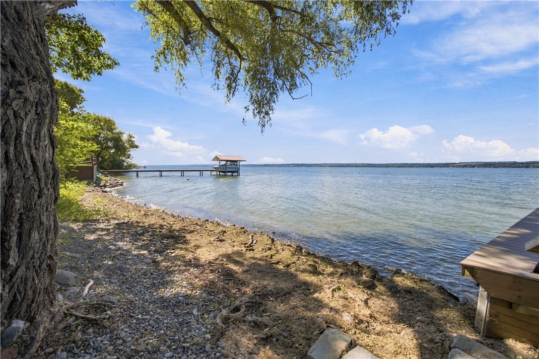 Rocky, tree-shaded lakefront with a long dock and covered boat lift.
