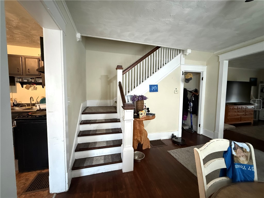 Entryway with a staircase featuring dark wood treads and white railings, between the kitchen and living room.