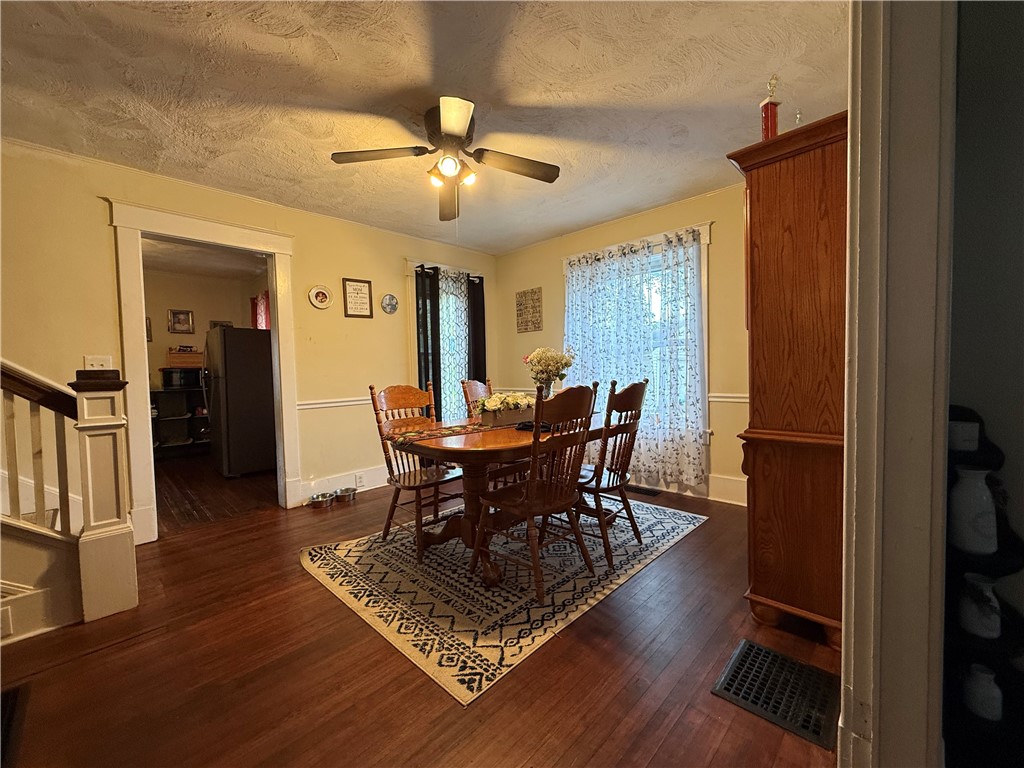 Dining room with a wooden table on a patterned rug and a tall wooden cabinet.