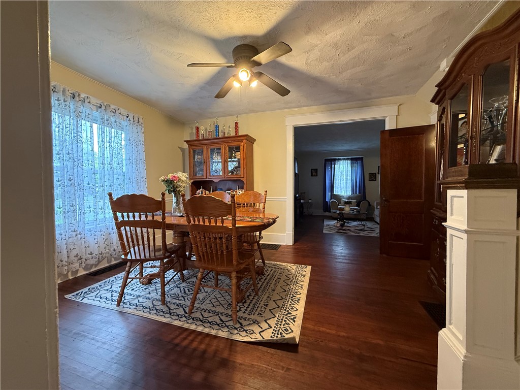 Dining room with a wooden table and chairs, patterned rug, and china cabinets beside an open doorway.