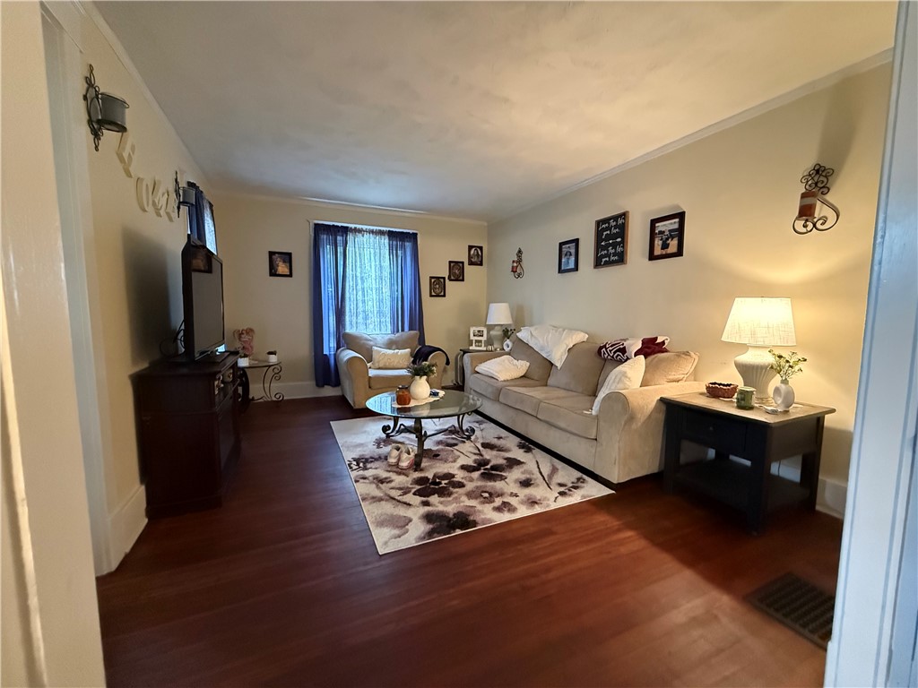 Furnished living room with a beige sofa, floral rug, and dark wood floors.