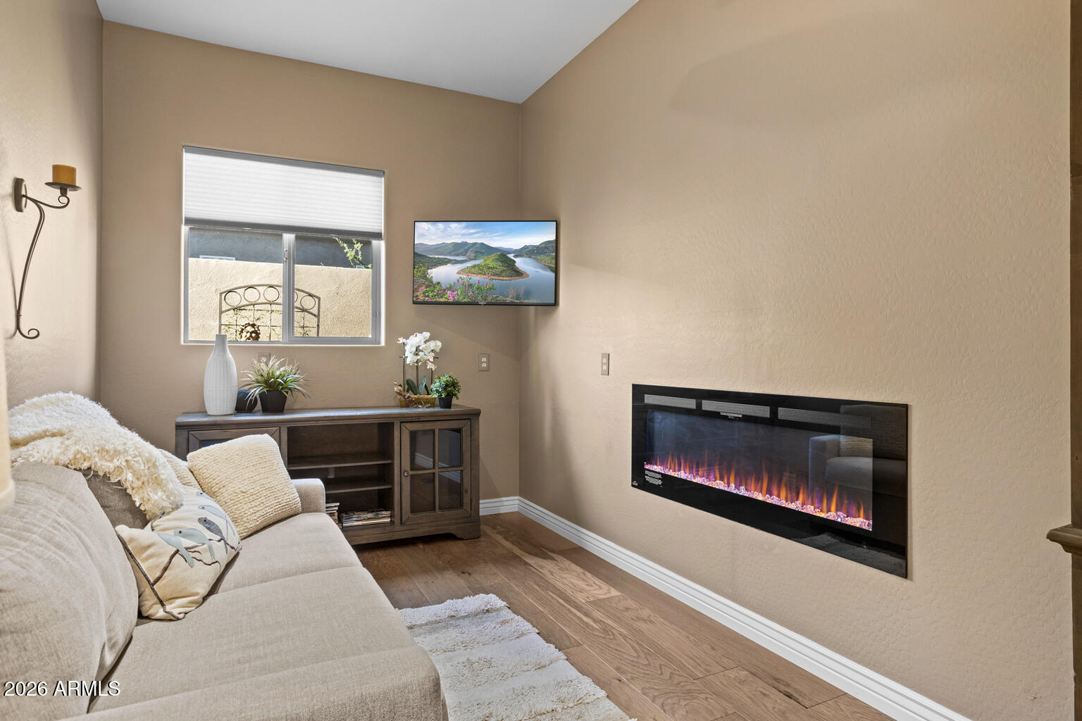 Living room with a sectional sofa and a long, wall-mounted electric fireplace.