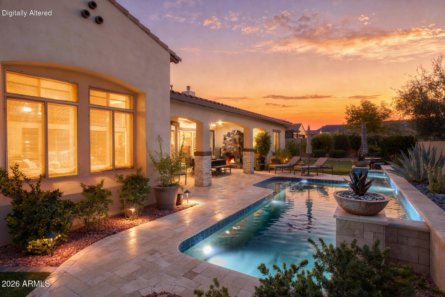 Home exterior at dusk with a backyard pool, covered patio, and outdoor fireplace.