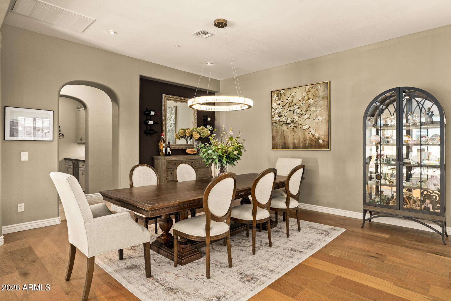 Dining room with a dark wood table, upholstered chairs, and a glass-front display cabinet.