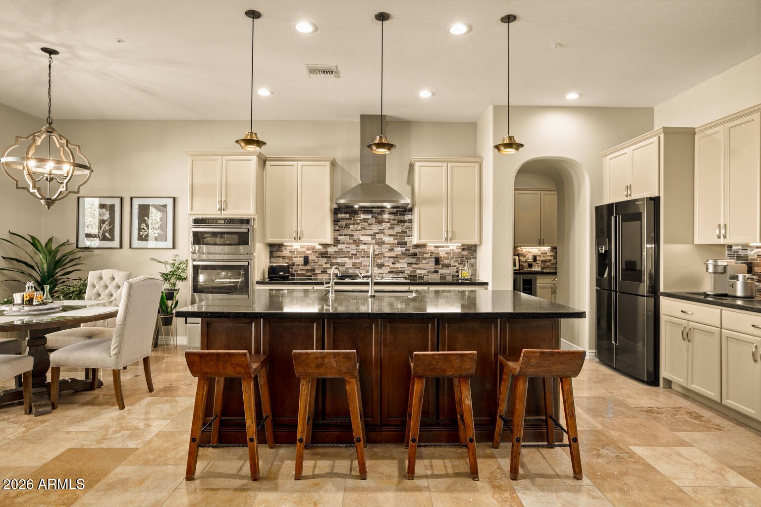 Kitchen with a large dark wood island, bar stools, cream cabinets, and stainless steel appliances.