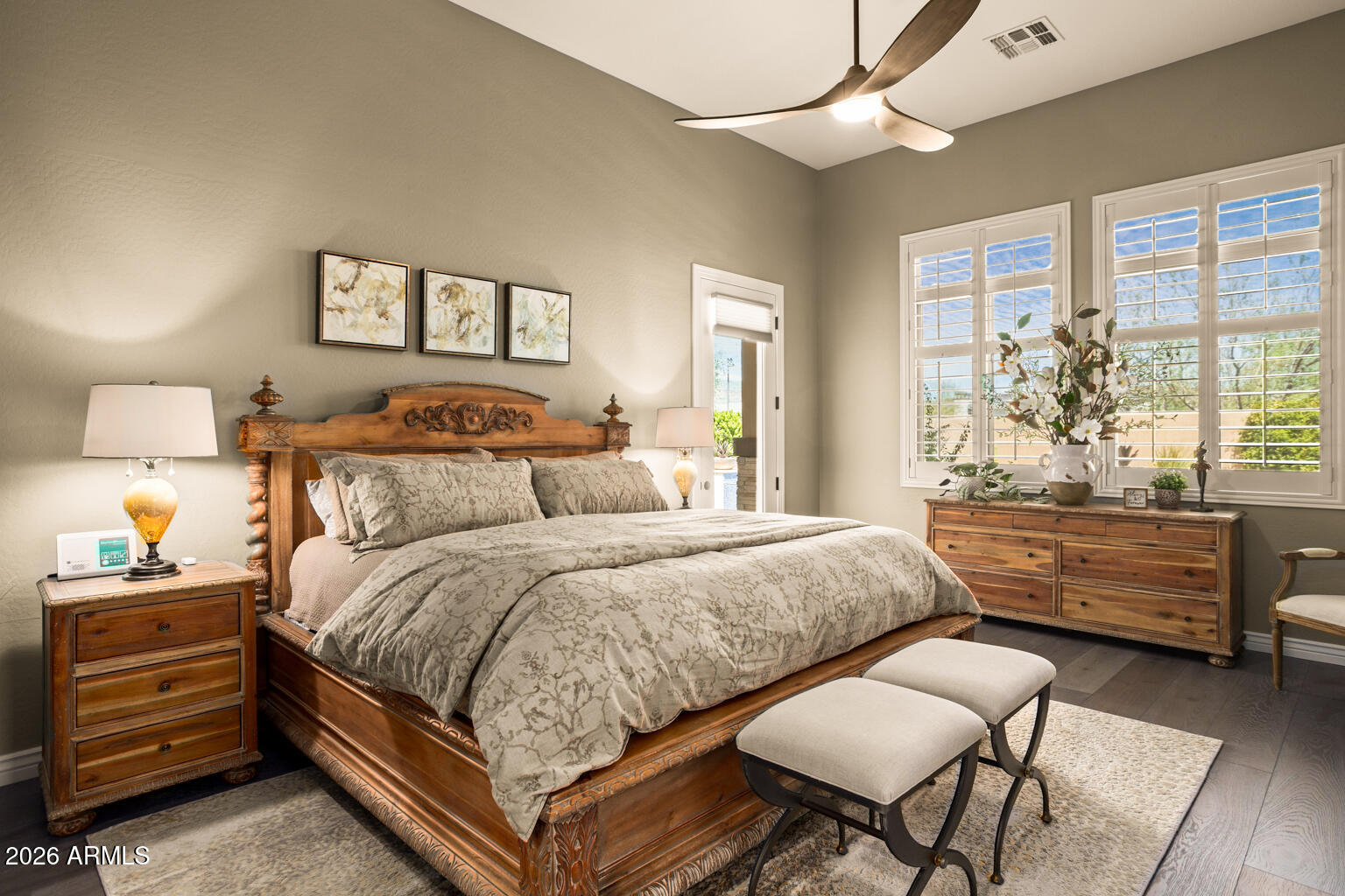Bedroom with a carved wooden bed, patterned bedding, and wide shuttered windows.