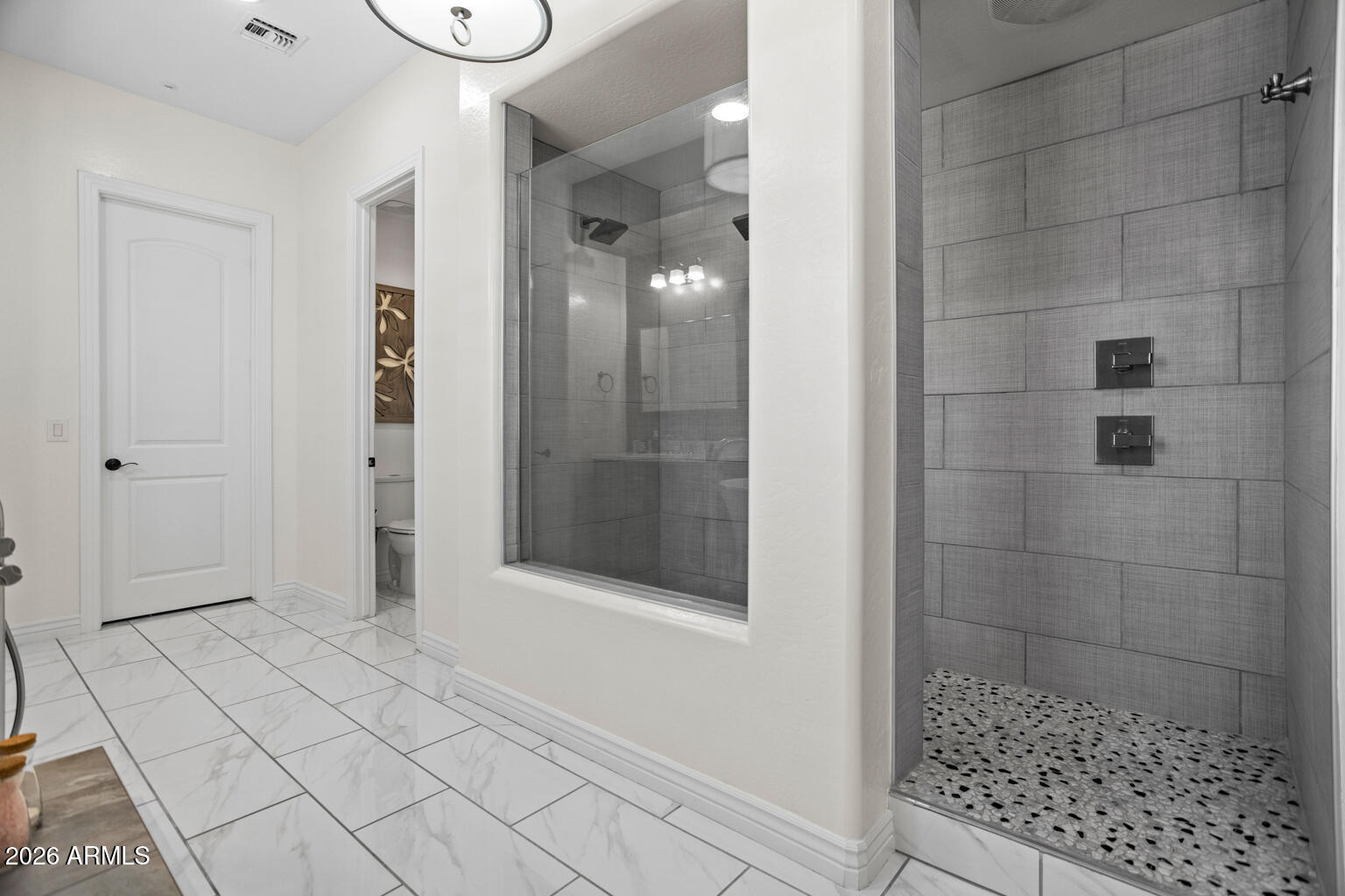Modern bathroom with a spacious tiled walk-in shower and pebble floor.