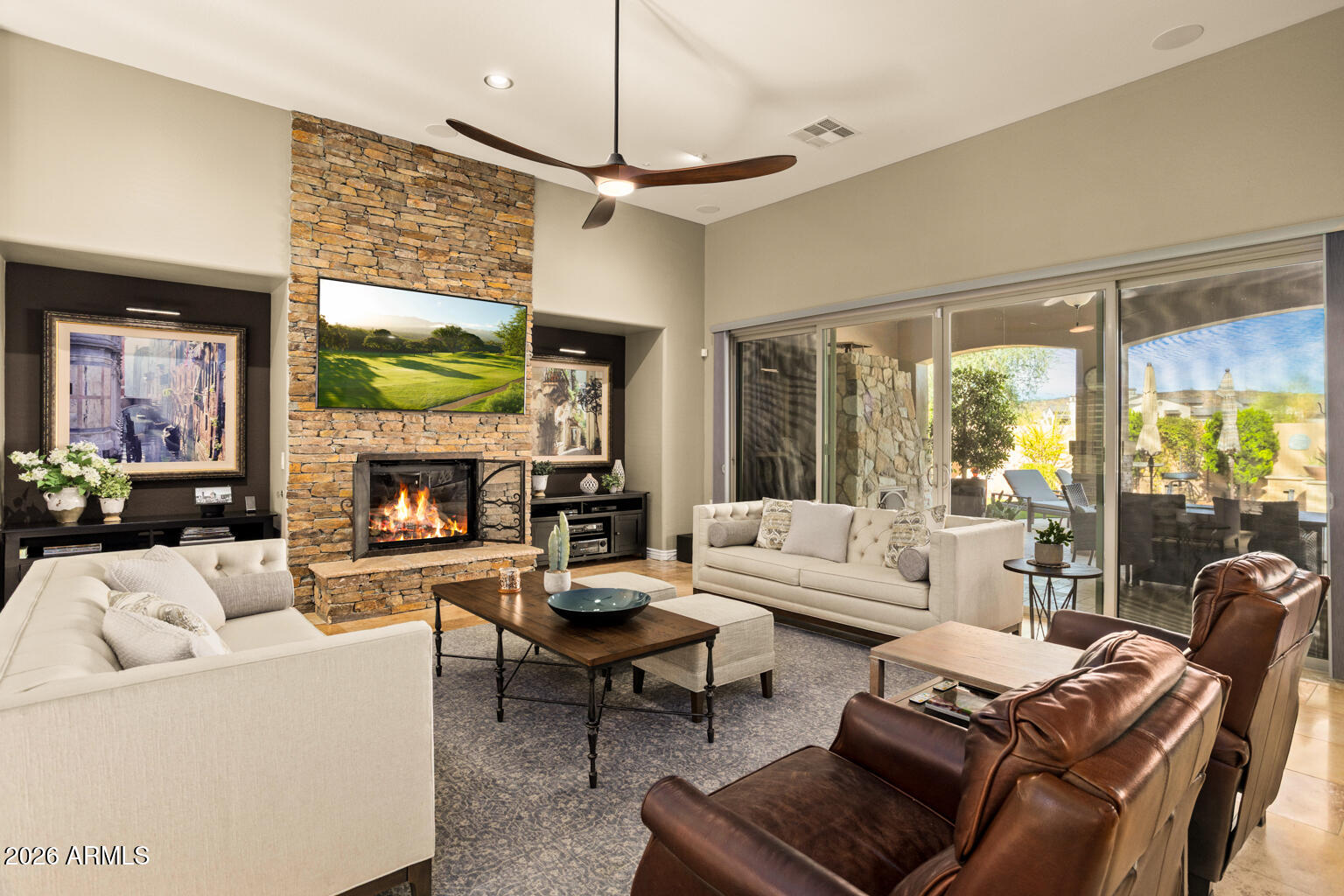 Living room with a stone fireplace, mixed seating, and sliding glass doors to a patio.