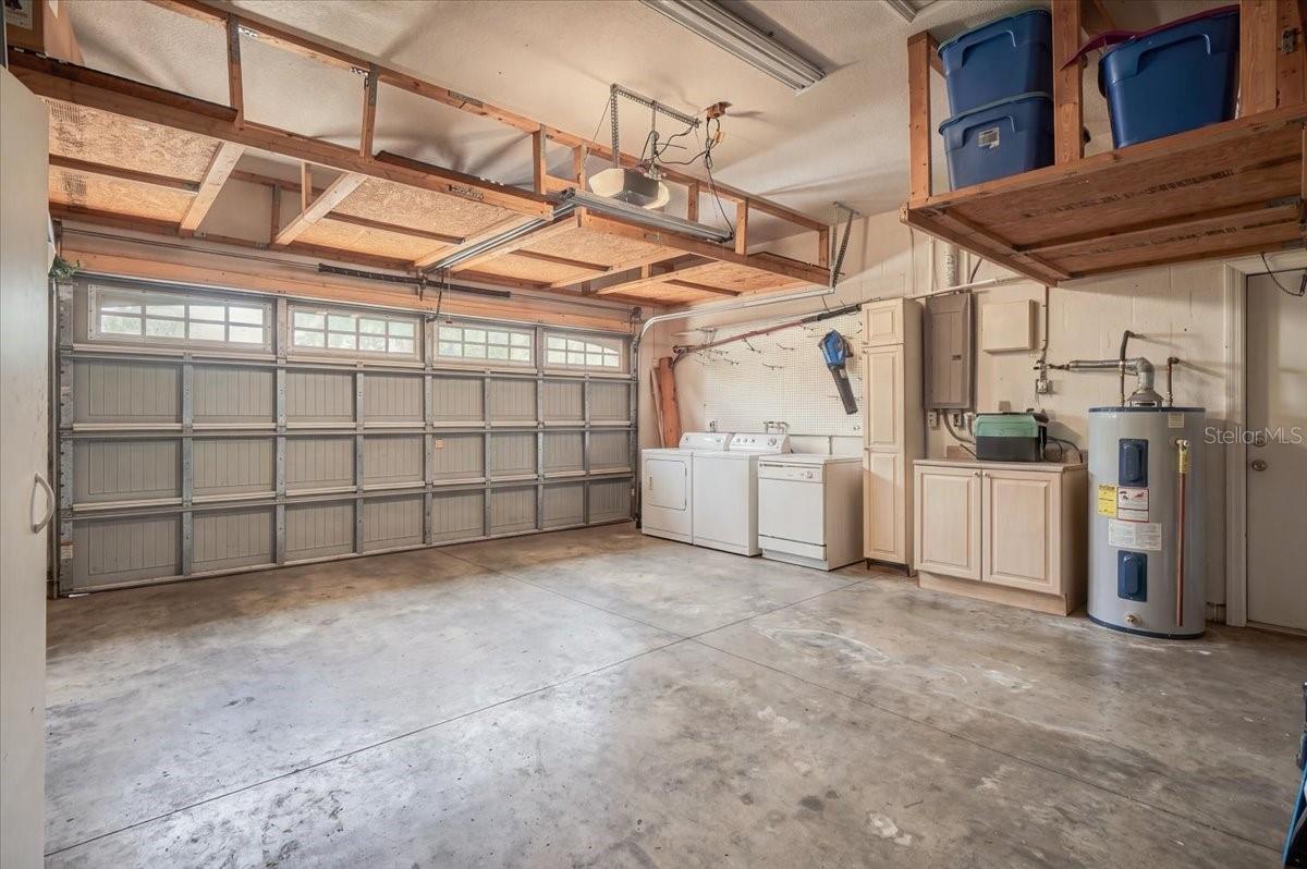 Garage with overhead storage, washer and dryer, utility sink, and water heater.