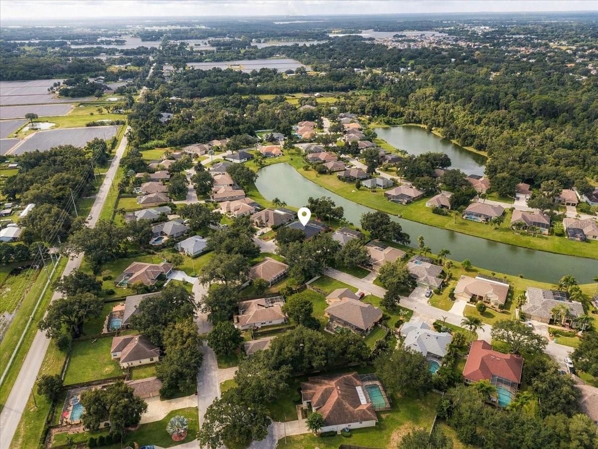 Aerial view of a home in a leafy neighborhood beside two ponds.