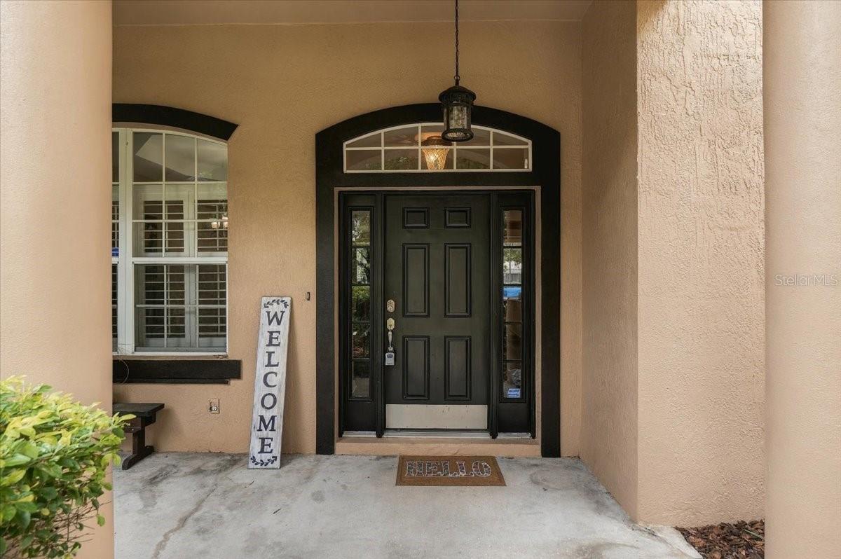 Home’s front entry with a black door, arched transom window, and covered porch.