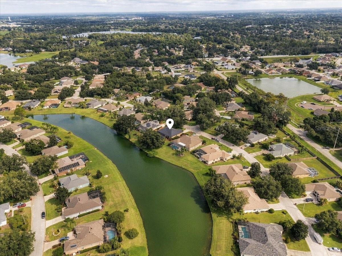 Aerial view of the marked home beside a winding waterway in a leafy residential neighborhood.