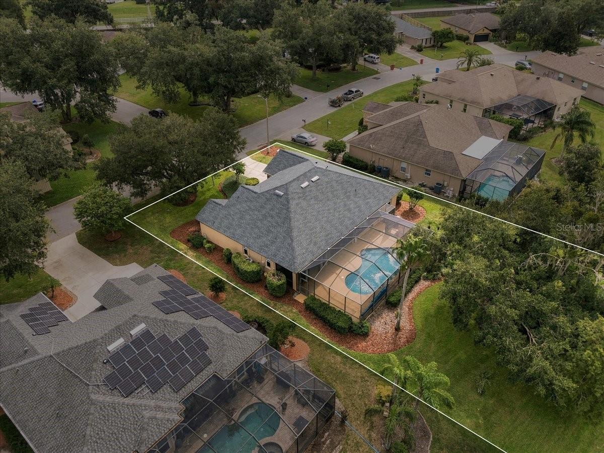 Aerial view of a home with a screened backyard pool and its property boundary outlined.