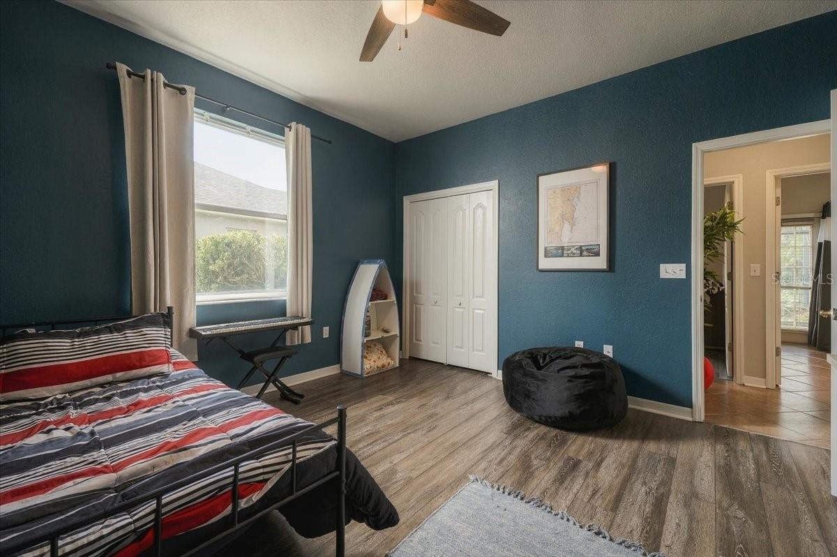 Bedroom with dark teal walls, a striped bed, and a black beanbag chair.