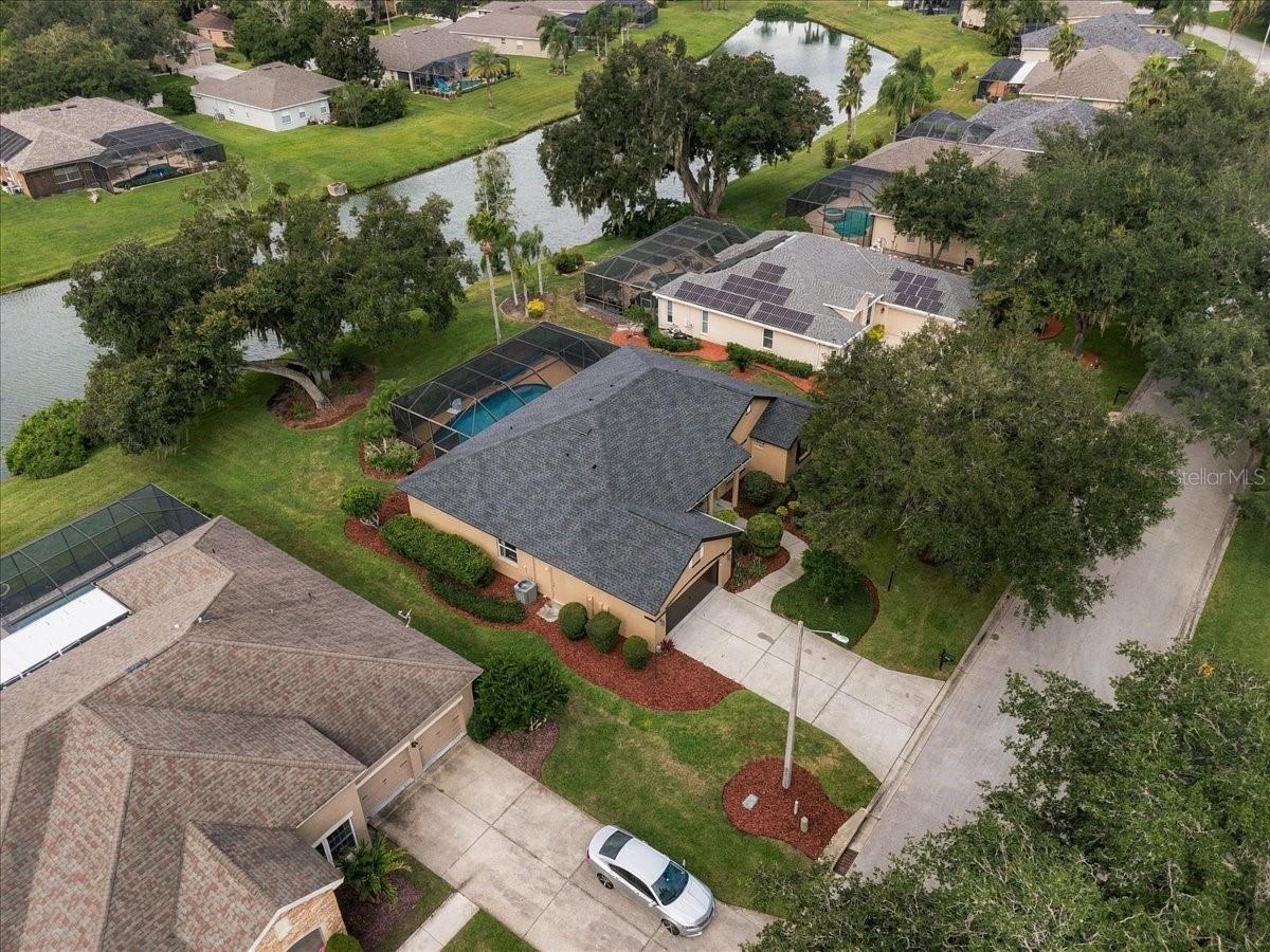 Aerial view of a tan home with a gray roof and landscaped yard near a canal.