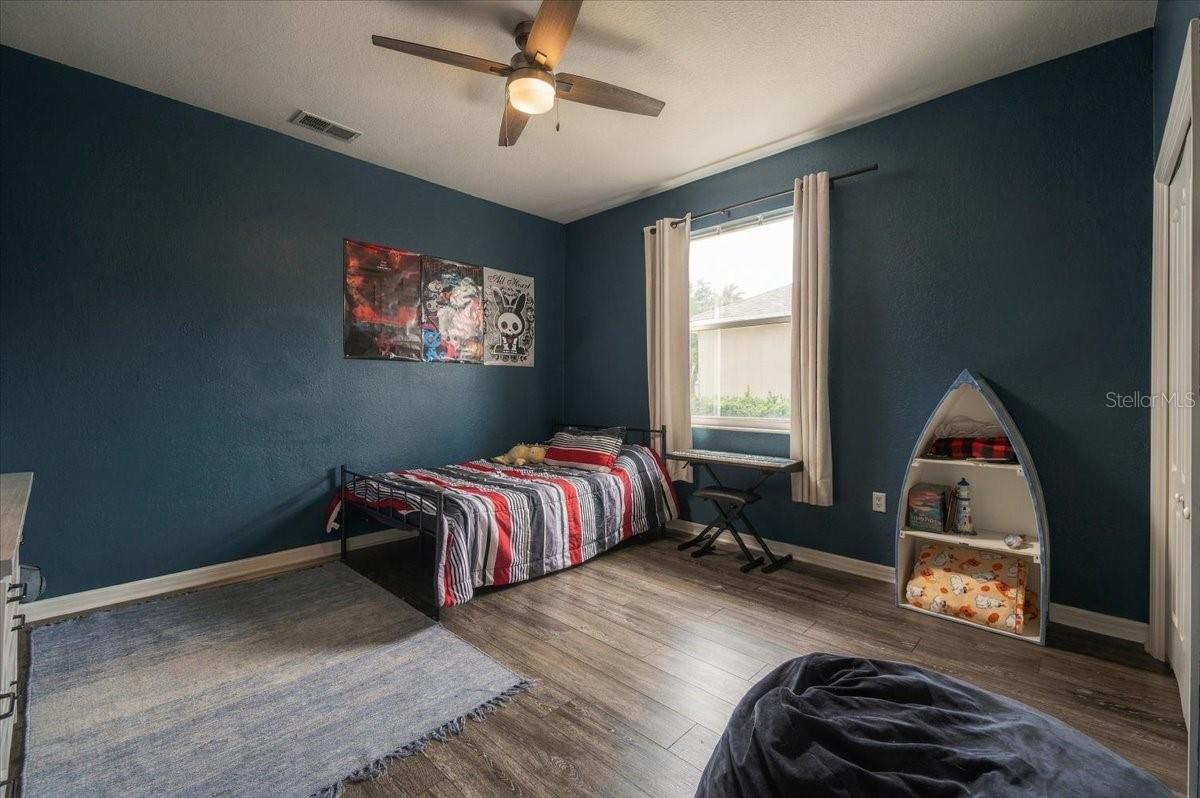 Bedroom with dark teal walls, a striped bed, and boat-shaped shelving beside the window.