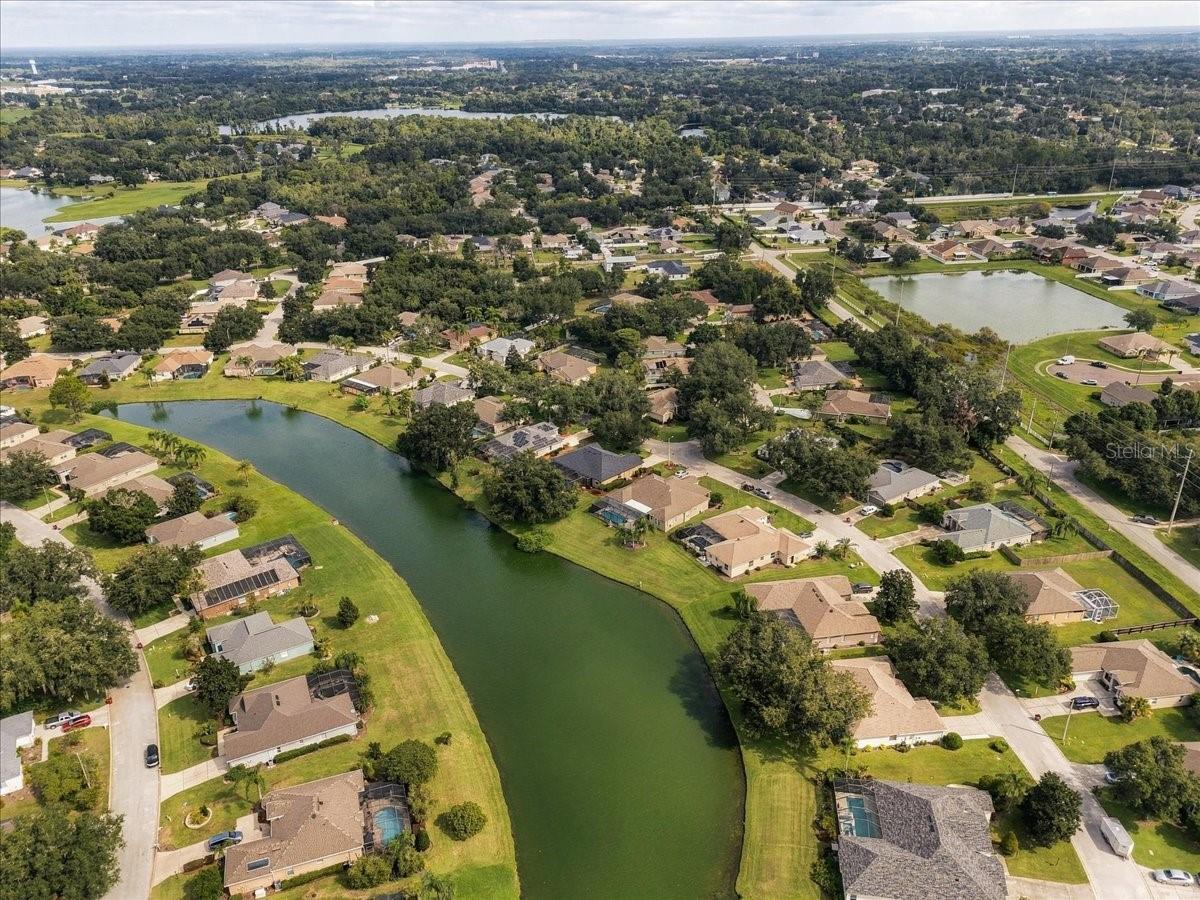 Aerial view of homes along a winding canal in a tree-lined residential neighborhood.