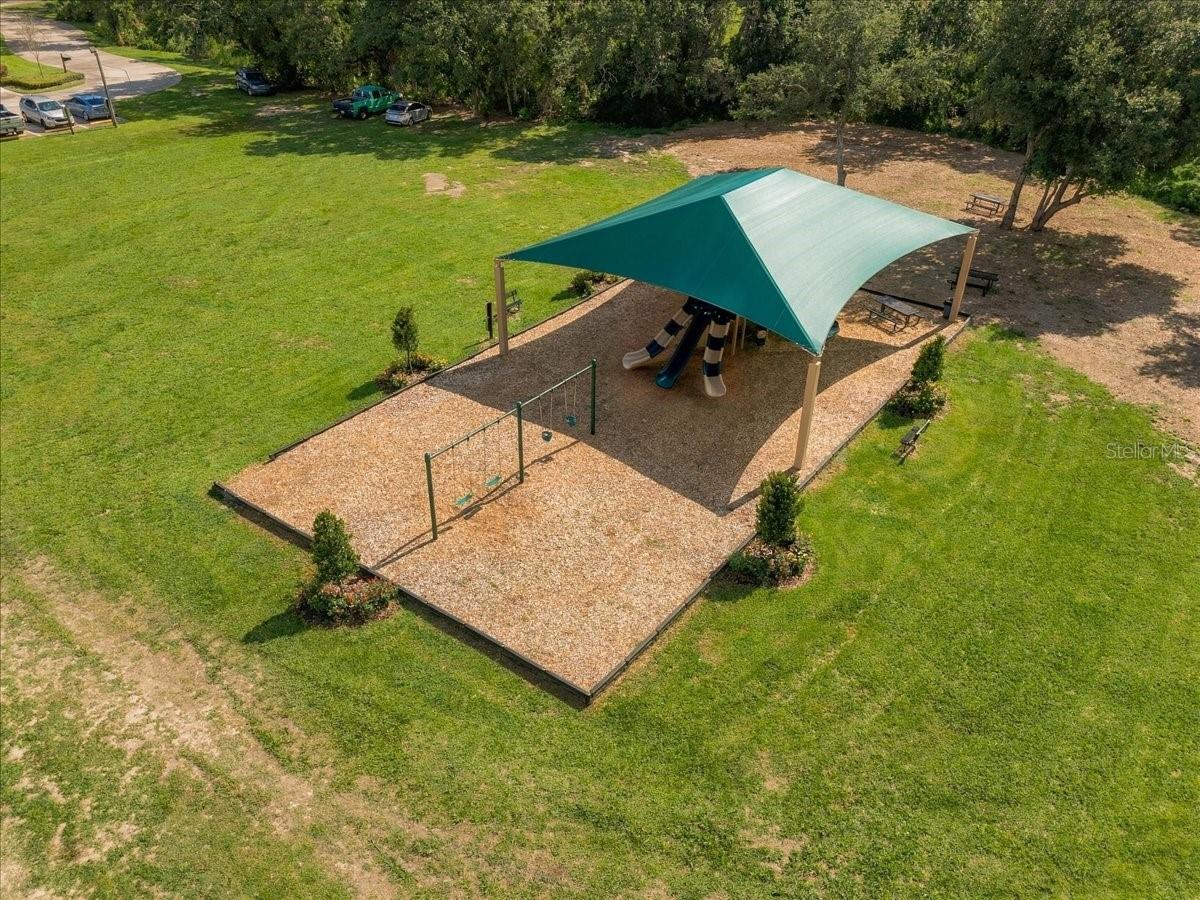 Community playground with slides and swings beneath a teal shade canopy.