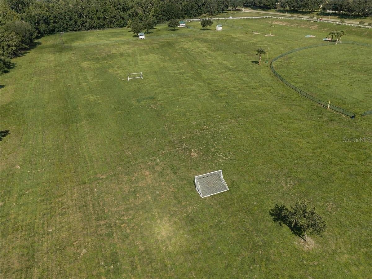 Aerial view of a grassy field with soccer goals and a fenced section.