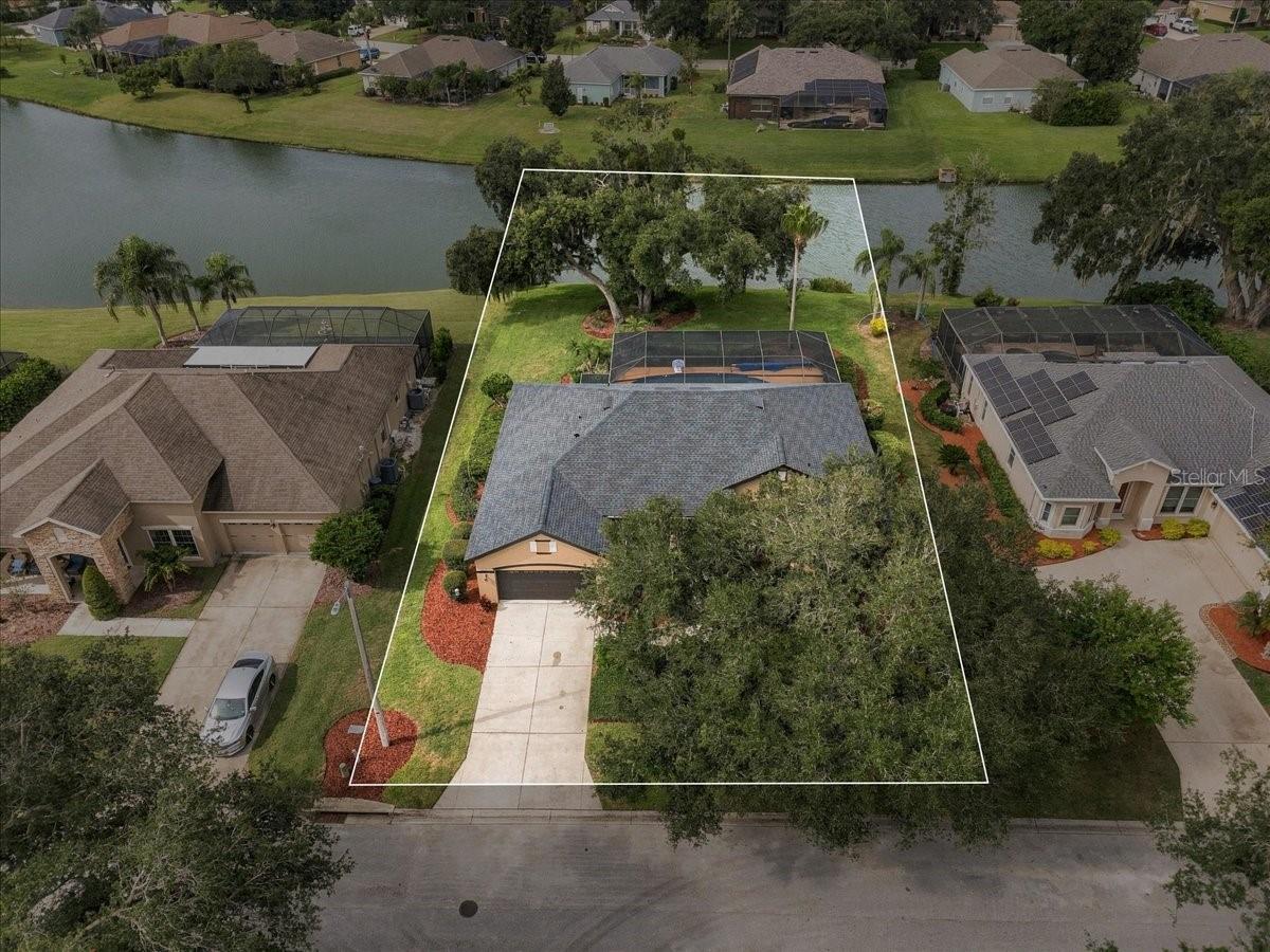 Aerial view of a canal-front home with a screened pool and outlined property lot.