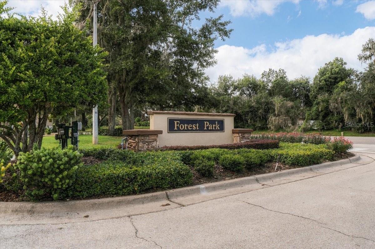 Forest Park community entrance sign amid landscaped shrubs and mature trees.