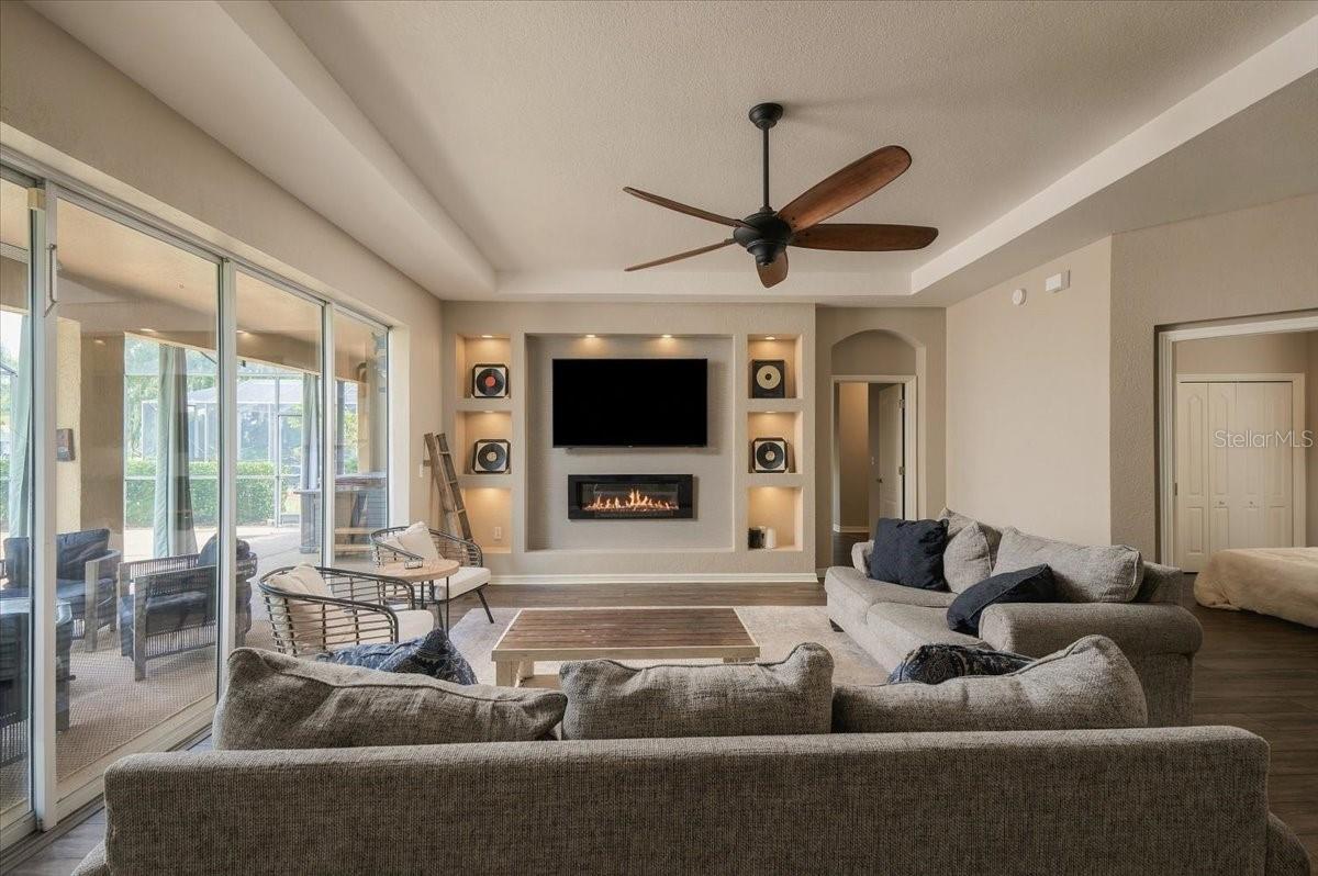 Living room with sectional seating, a television above a fireplace, and sliding doors to a screened patio.