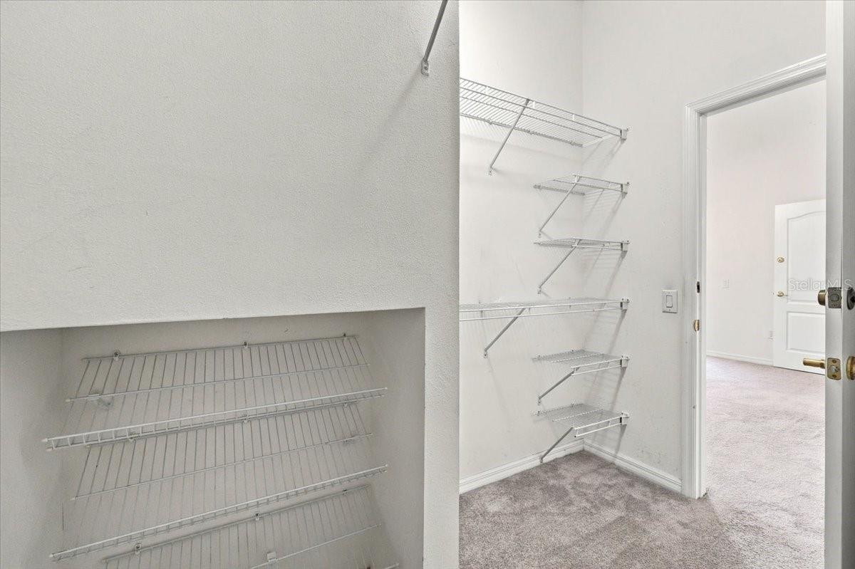 Walk-in closet with white wire shelving and carpeted floor.