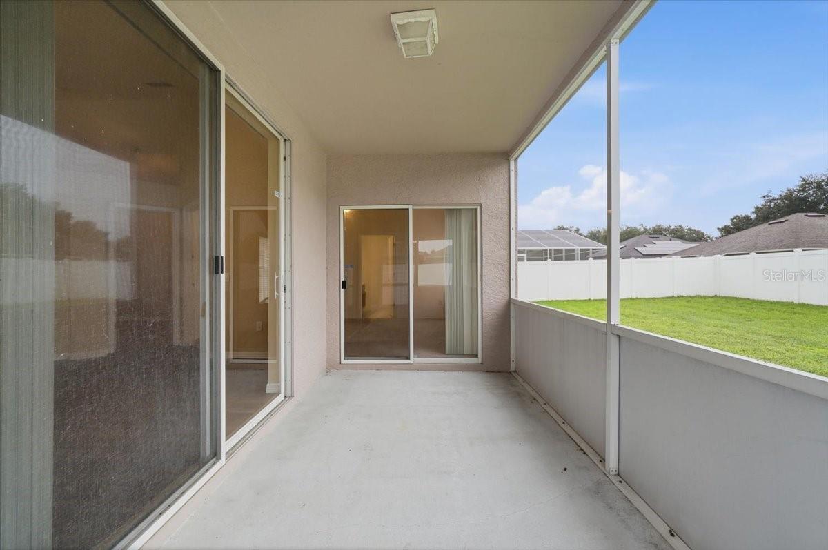 Covered concrete patio with sliding glass doors and a fenced backyard.