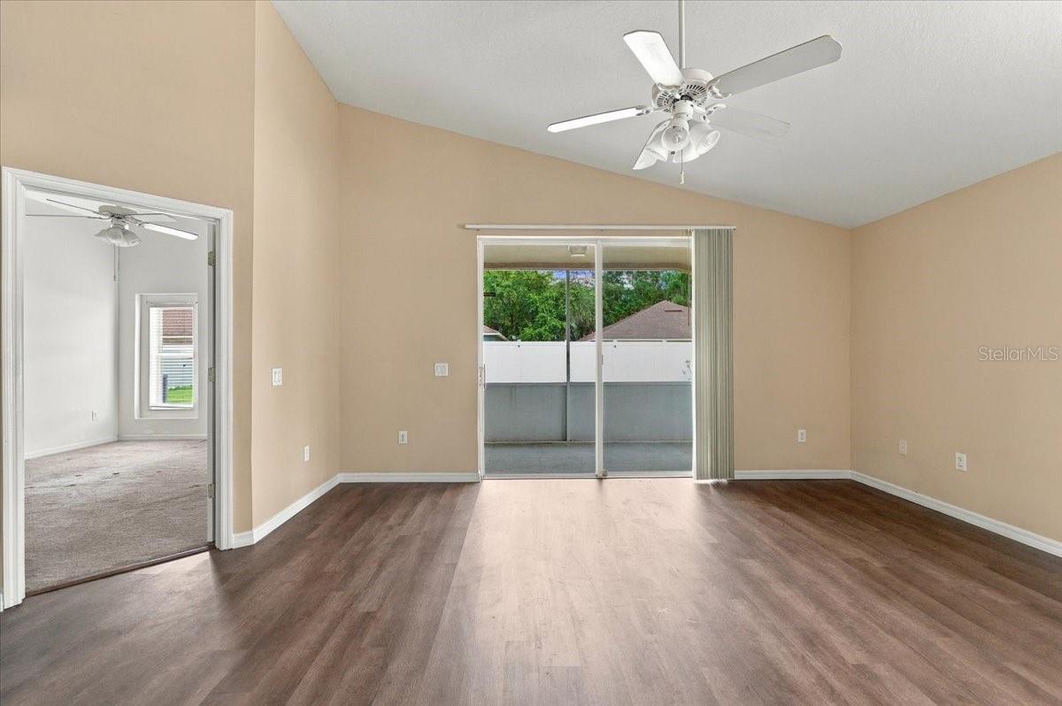 Empty room with wood-look flooring, a ceiling fan, and sliding glass doors to a covered patio.