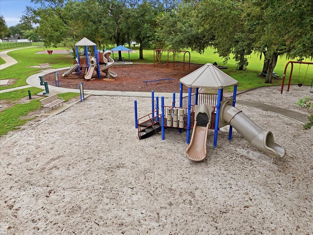 Community playground with multiple slides, swings, and shaded play structures.