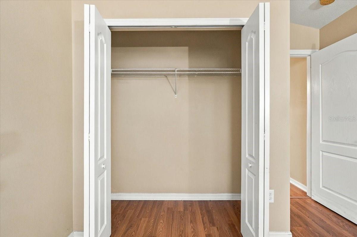 Open closet with a wire shelf and wood flooring.