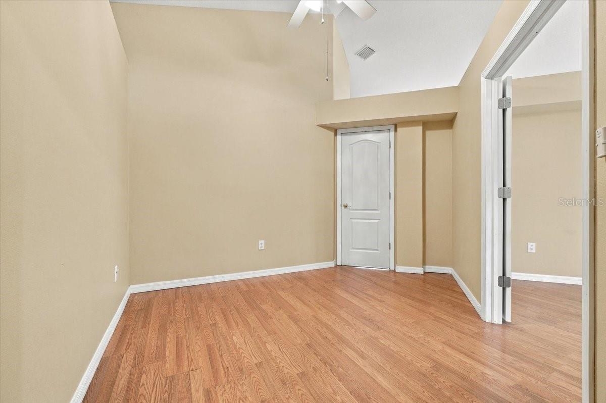 Empty room with hardwood floors, beige walls, and a white door.