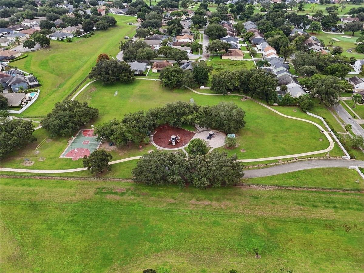 Aerial view of a neighborhood park with a basketball court, playground, and walking paths.