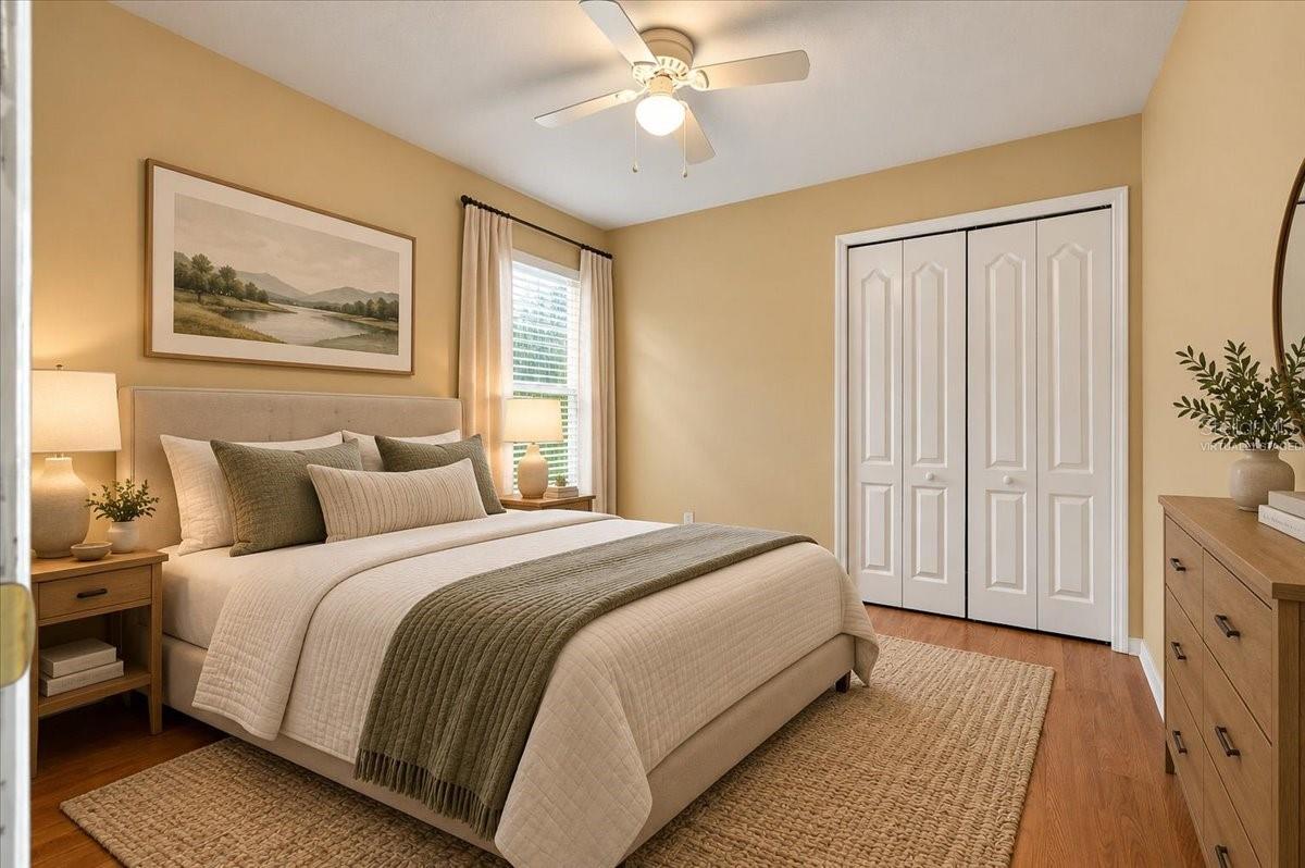 Staged bedroom with a neutral upholstered bed, woven rug, and white double closet doors.