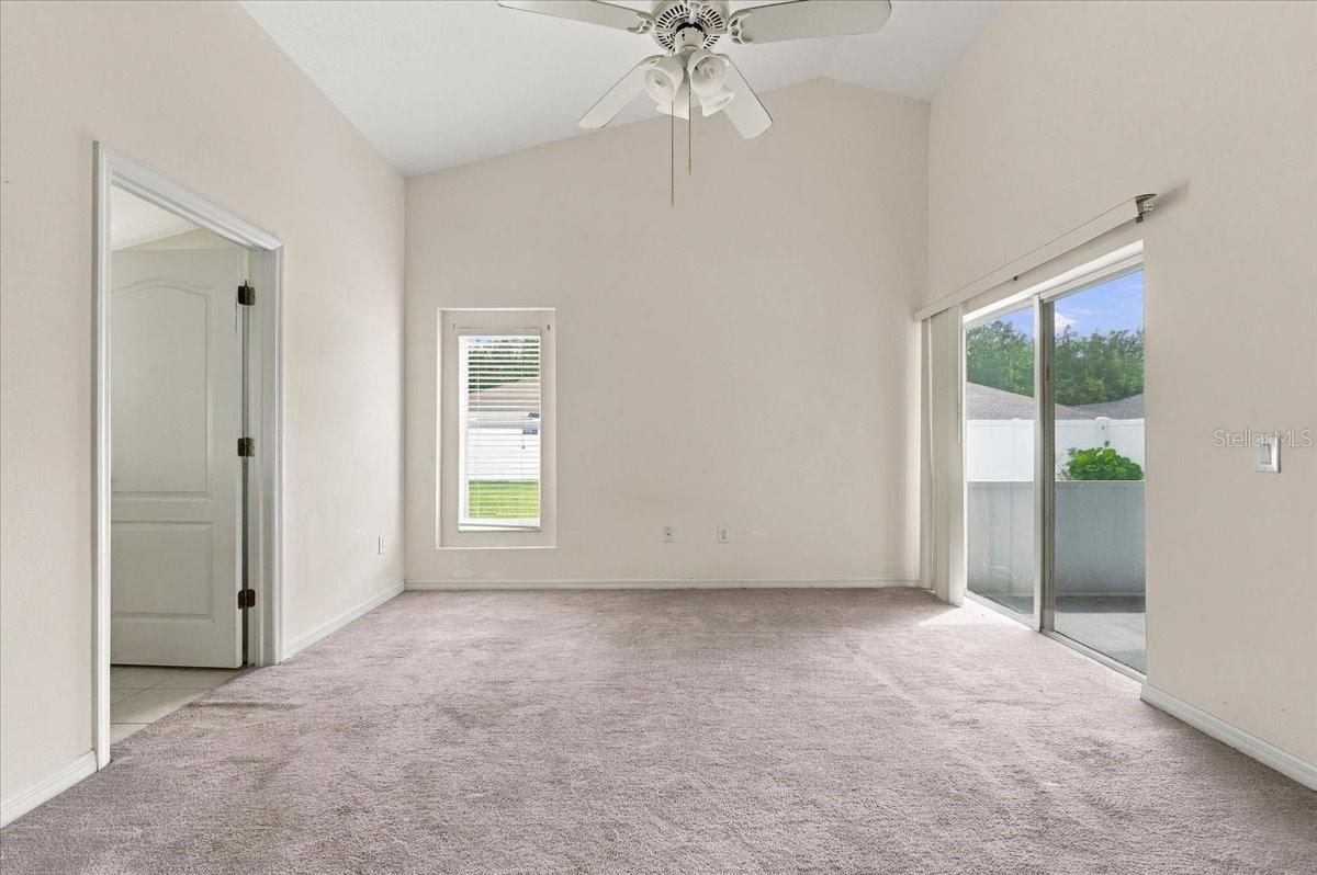 Unfurnished carpeted bedroom with a ceiling fan and sliding glass doors to a patio.