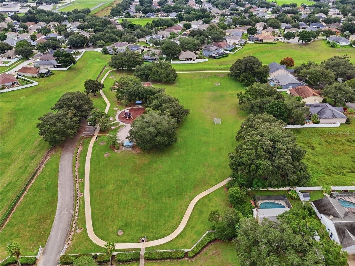 Aerial view of a neighborhood green with walking paths, playground, and surrounding homes.