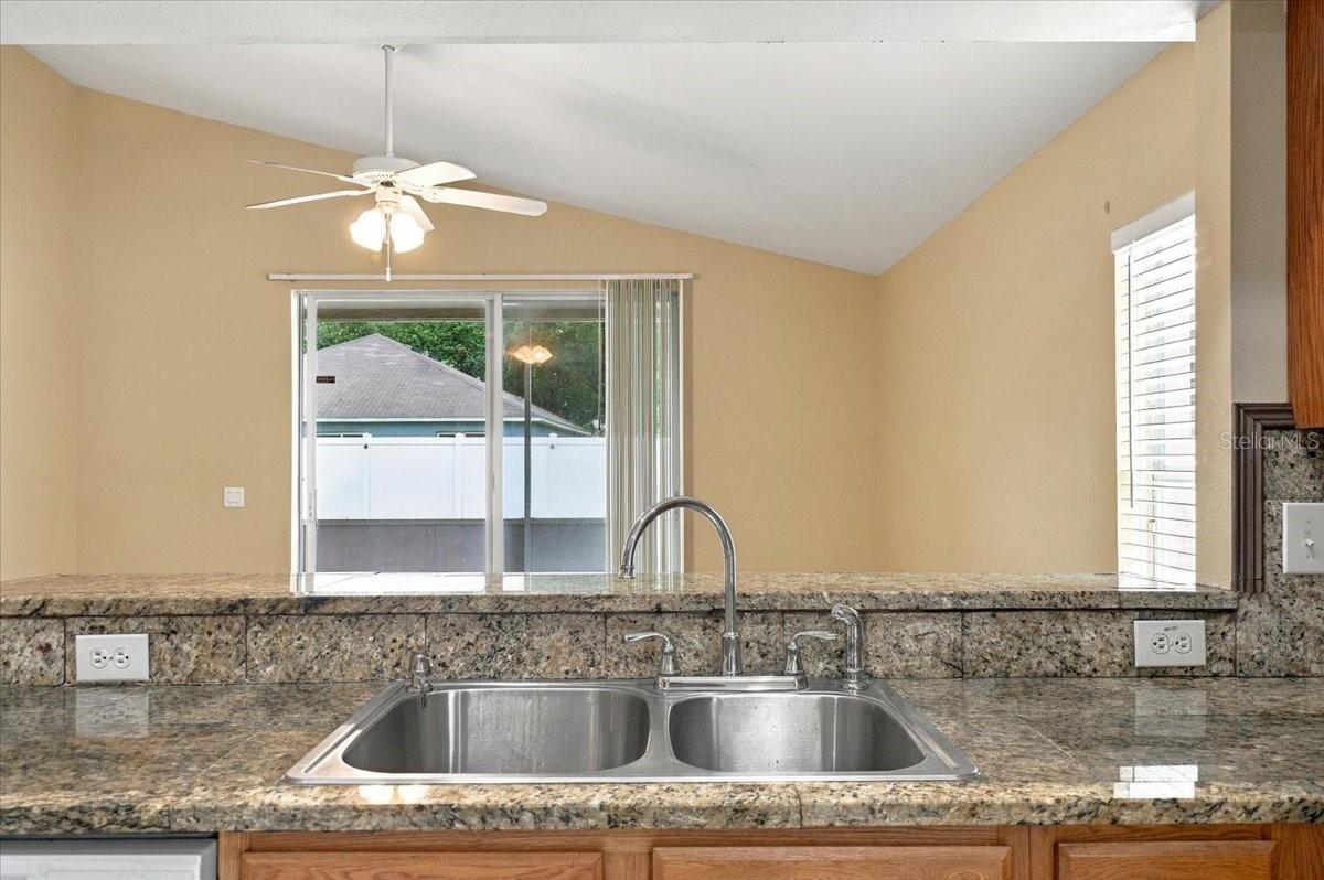 Kitchen with granite counters and double sink facing a sliding glass door.