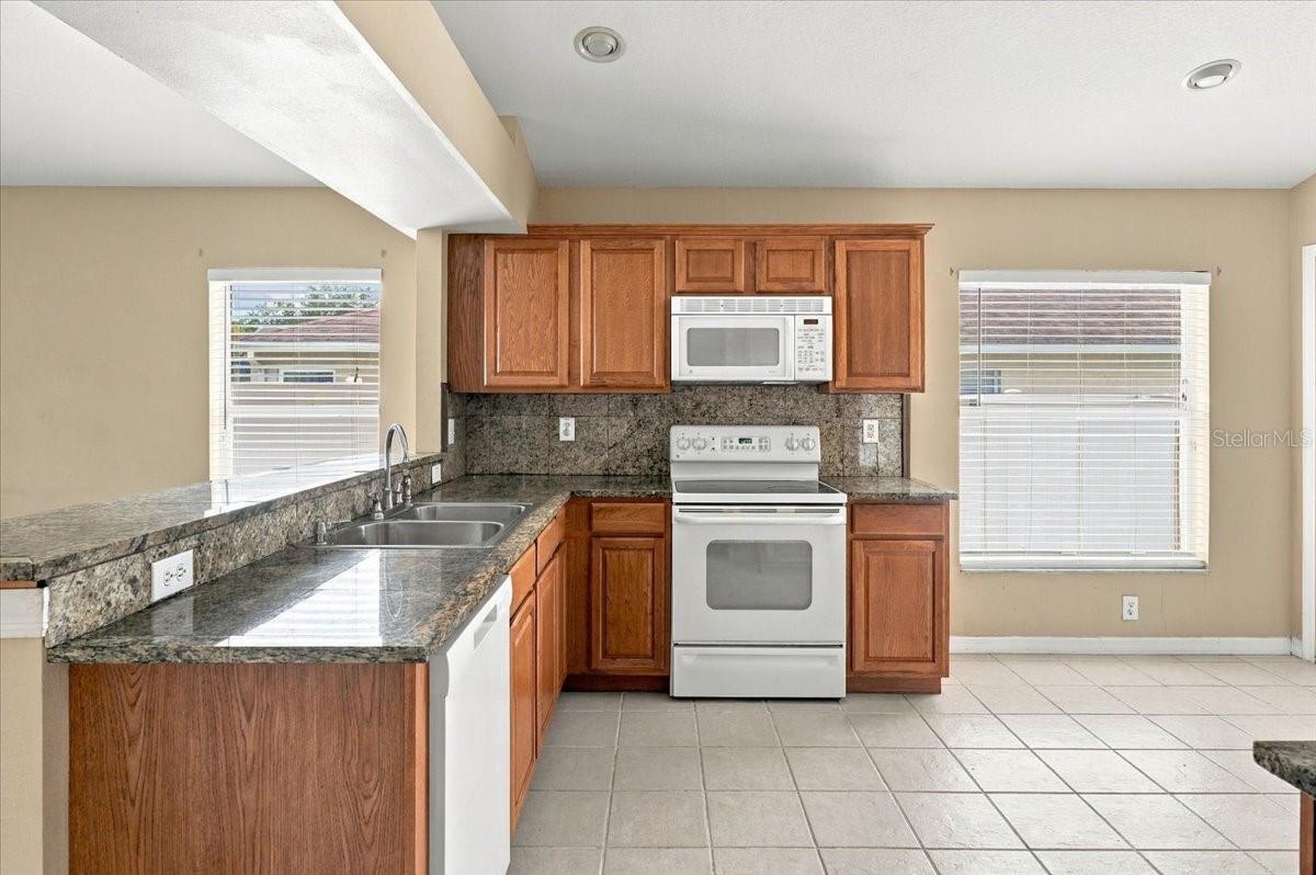 Kitchen with wood cabinets, granite counters, and white appliances.