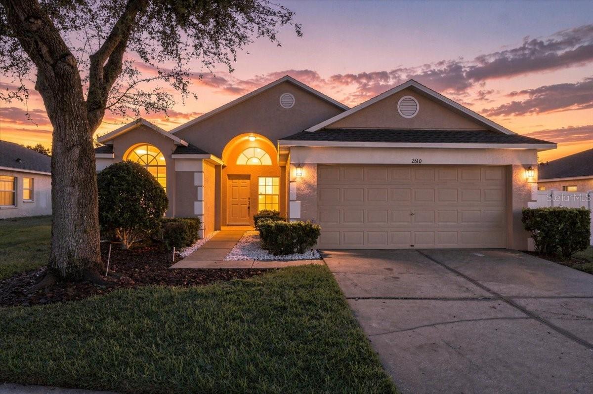 Single-story home with an arched entry and two-car garage at sunset.