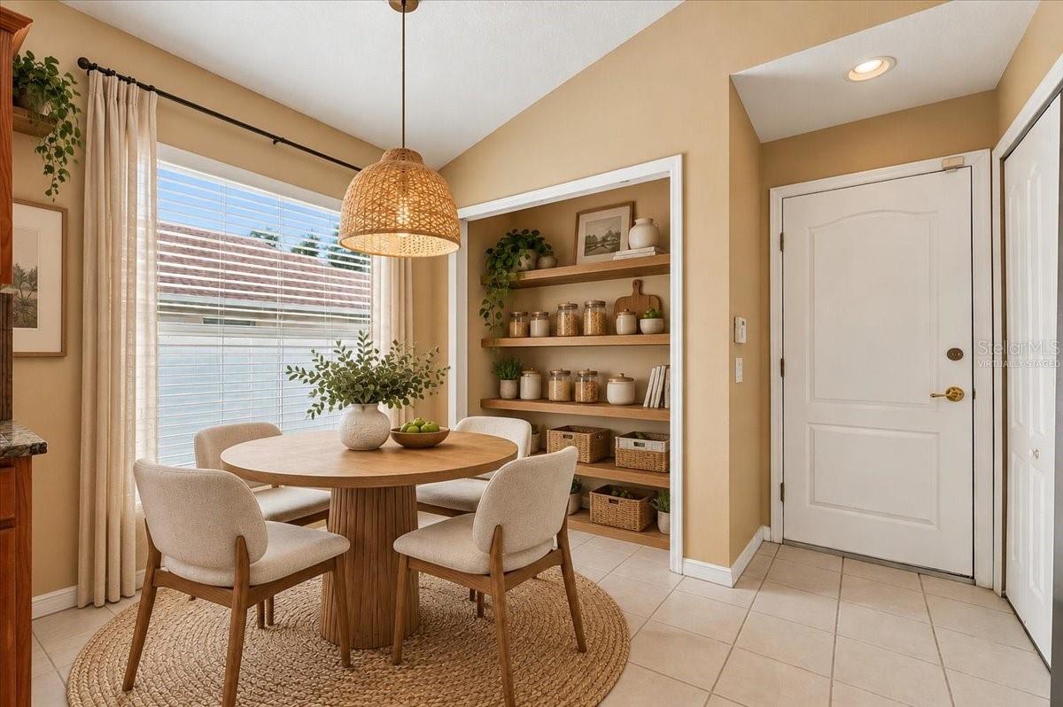 Staged dining nook with a round wooden table, woven pendant light, and built-in open shelves.