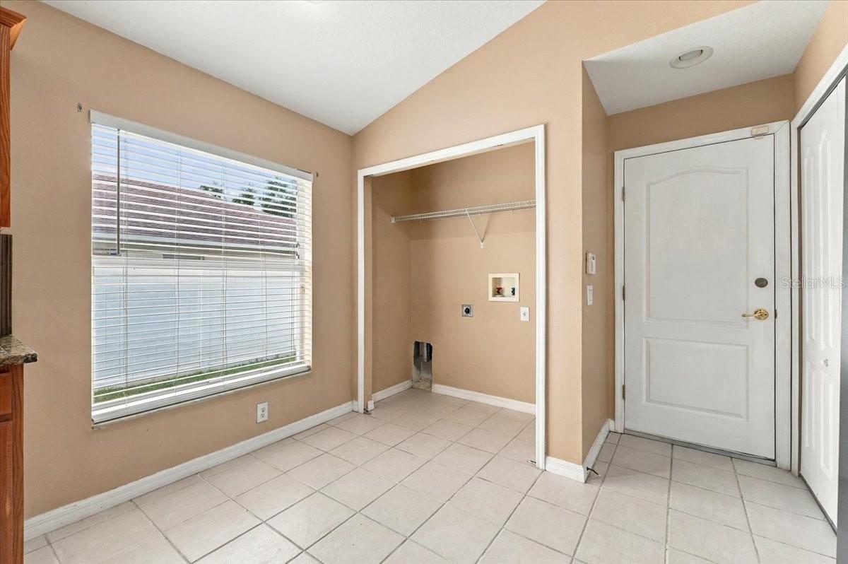 Laundry area with washer and dryer hookups, a window with blinds, and tiled flooring.