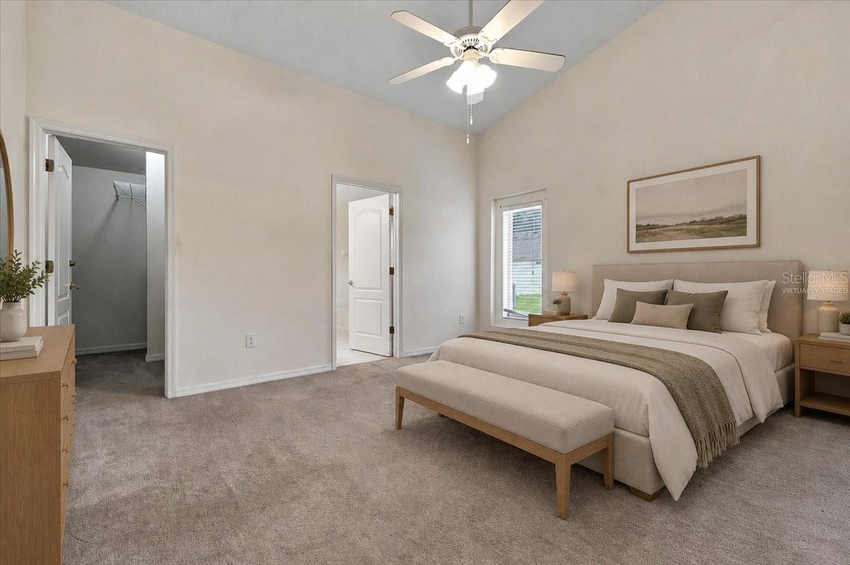 Staged bedroom with a king bed, upholstered bench, and walk-in closet.