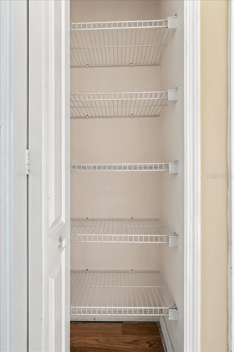 Empty pantry closet with multiple white wire shelves and wood flooring.