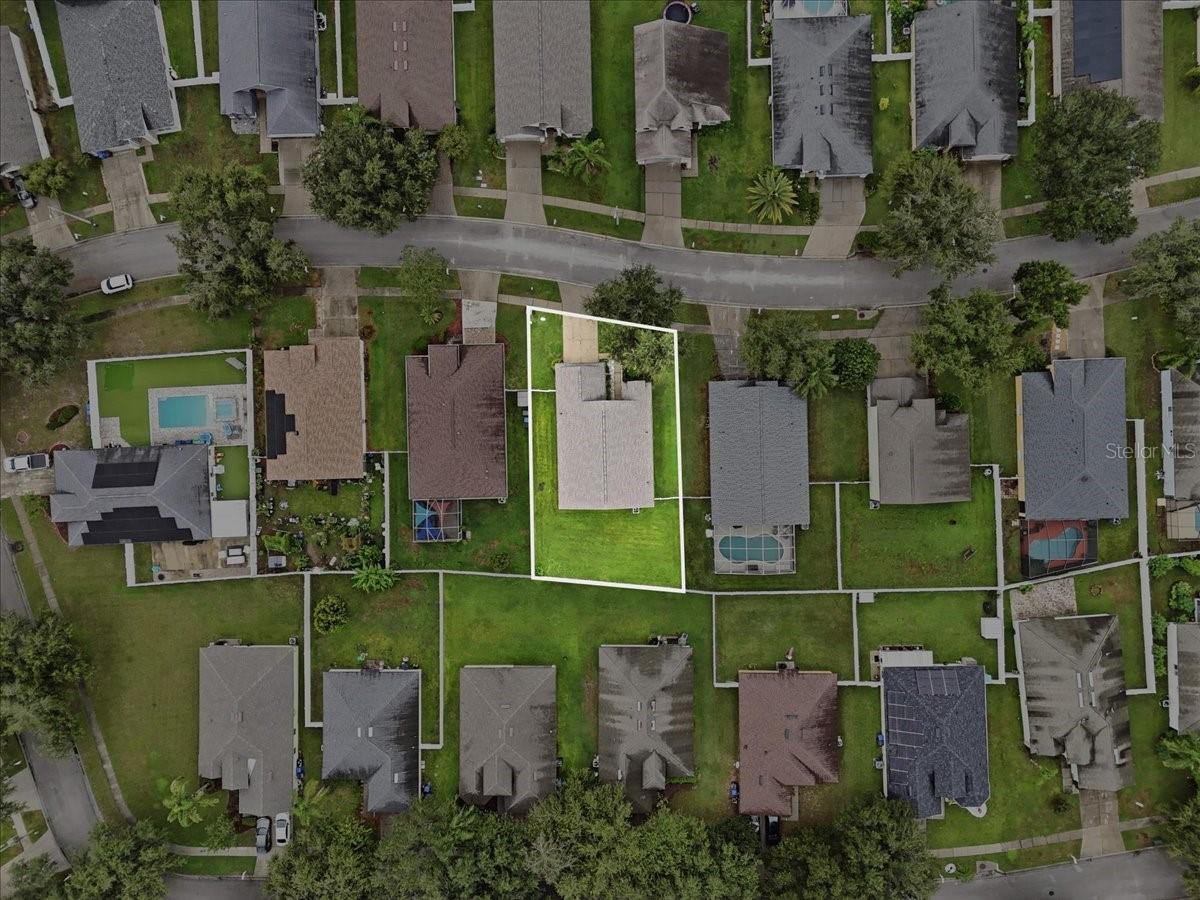 Aerial view of a home and its outlined lot among neighboring houses.