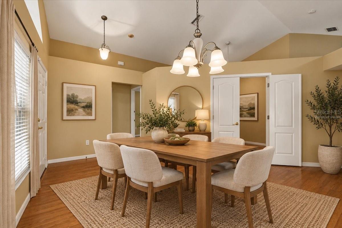 Dining room with a long wood table, upholstered chairs, and a large woven rug.