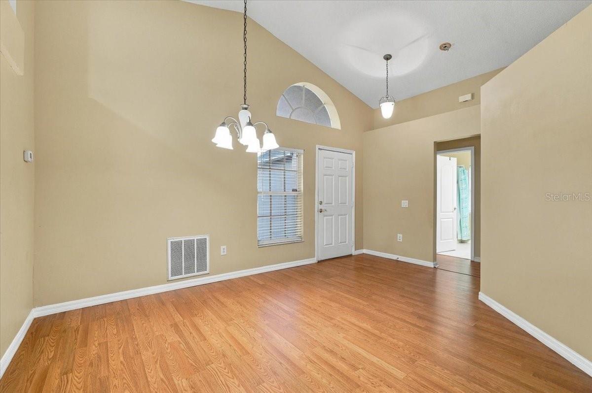 Vacant entry room with a high ceiling, wood flooring, and a chandelier.