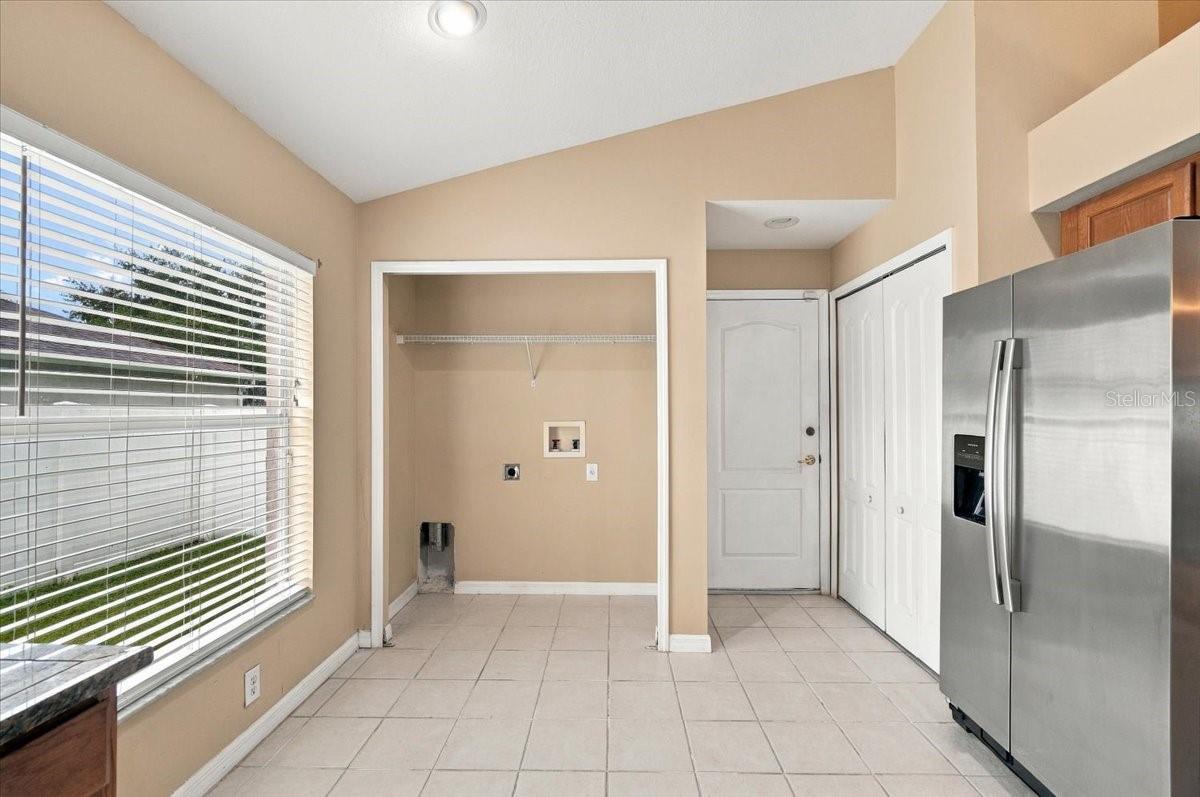 Laundry area with washer and dryer hookups beside a stainless steel refrigerator.