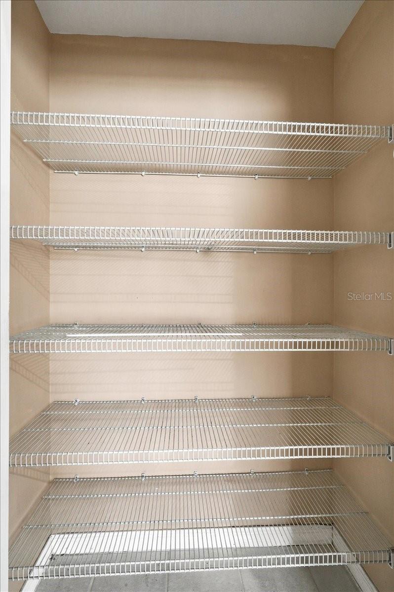 Walk-in closet with multiple empty white wire shelves.