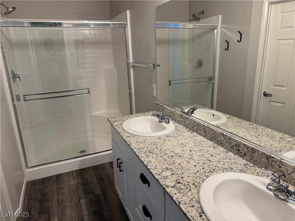 Bathroom with a double-sink granite vanity and a glass-enclosed, white-tile shower.