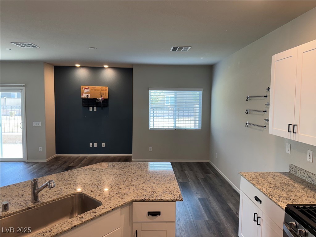 Kitchen with granite-pattern counters, white cabinets, and a dark accent wall.